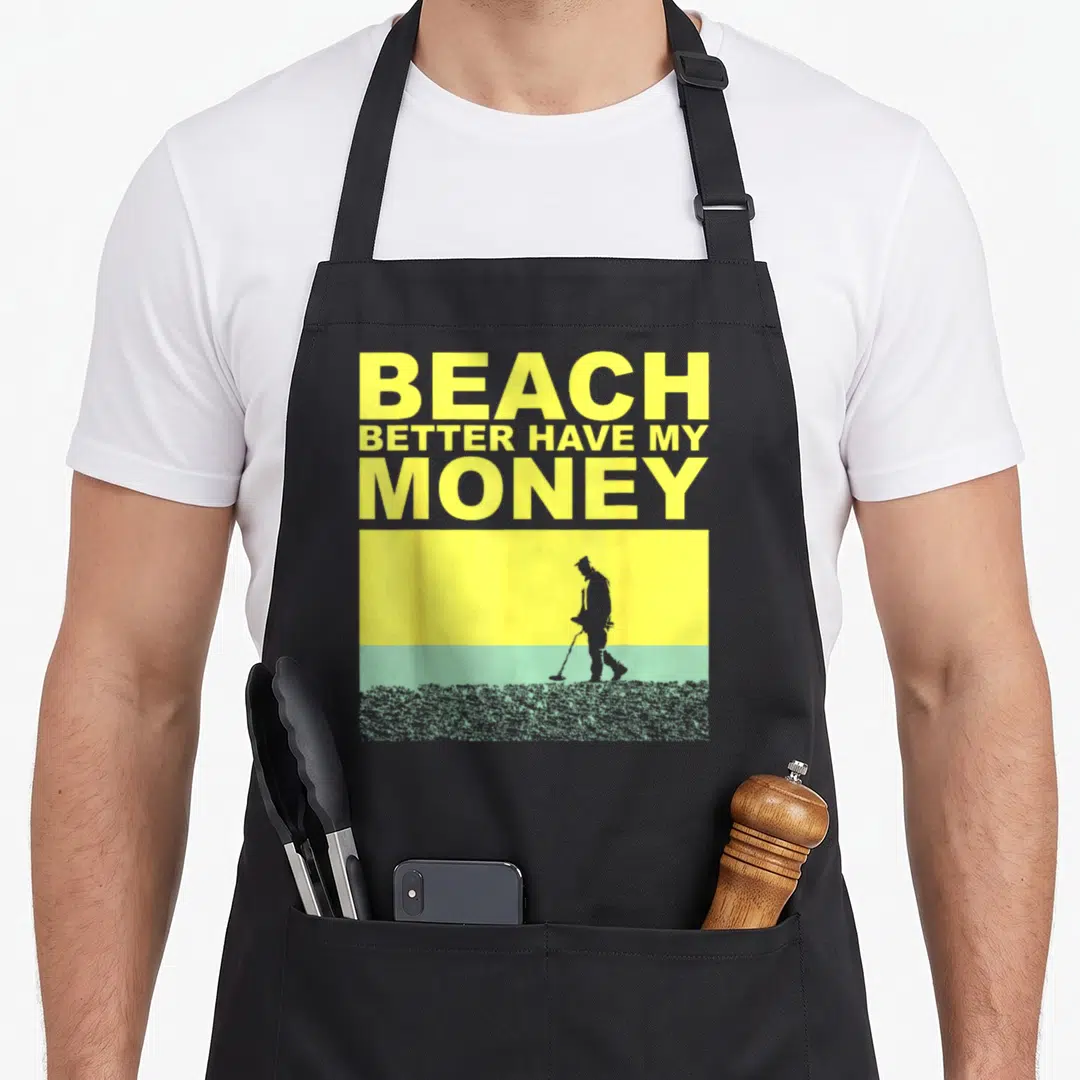Cute detectorist metal detecting apron - Yellow text BEACH BETTER HAVE MY MONEY above man silhouette on yellow sky — shown on a black cotton canvas apron against a white background