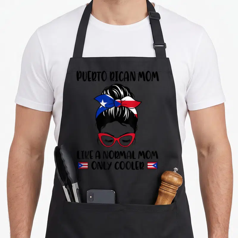 Puerto mother's day aprons - Woman with red glasses and flag bow, Puerto Rican Mom text, two small flags — shown on a black cotton canvas apron against a white background