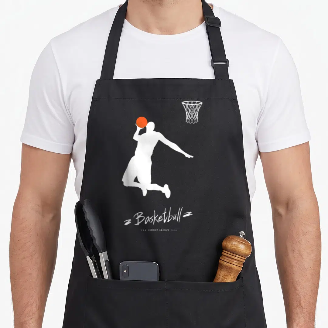 Basketball summer aprons - White jumping player silhouette holding orange ball with Basketball Summer League text — shown on a black cotton canvas apron against a white background
