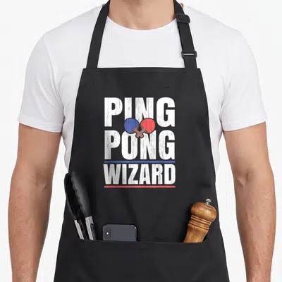Wizard table apron - Stacked PING PONG WIZARD text with crossed blue and red paddles and horizontal lines — shown on a black cotton canvas apron against a white background