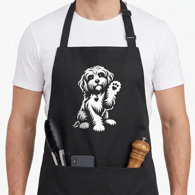 Retro cavapoo dog apron - White line art of a sitting dog raising a paw with a heart on its chest — shown on a black cotton canvas apron against a white background