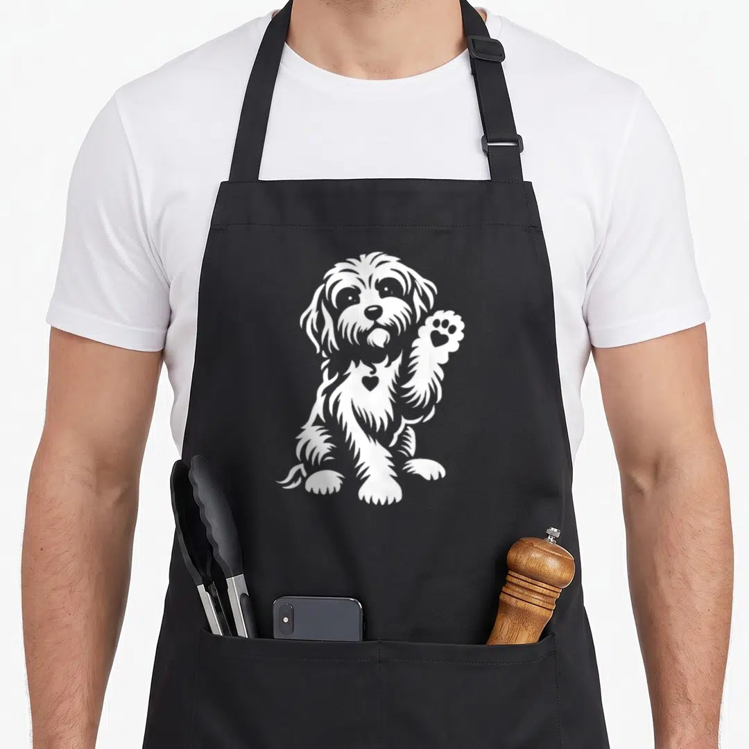 Retro cavapoo dog apron - White line art of a sitting dog raising a paw with a heart on its chest — shown on a black cotton canvas apron against a white background