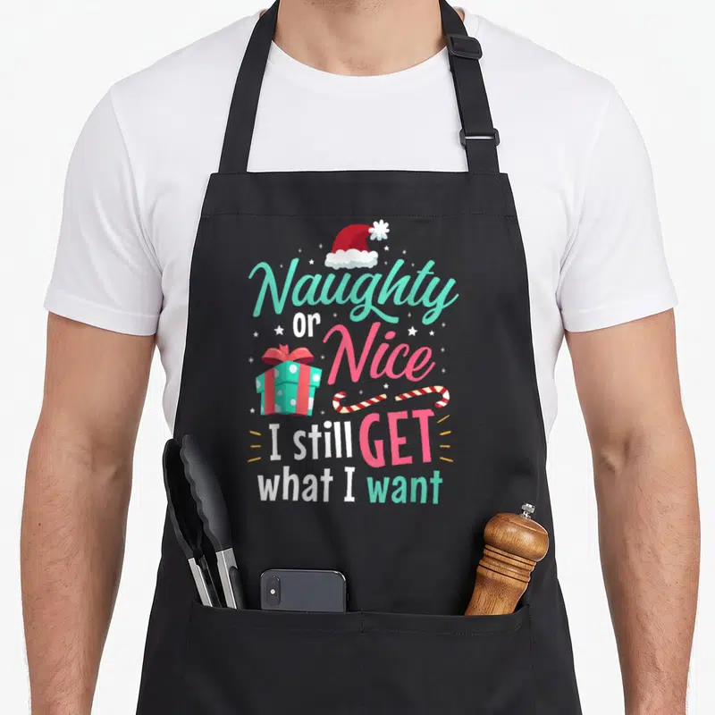 Cheeky womens christmas aprons - Santa hat, gift box, candy canes, and Naughty Nice text in teal and pink — shown on a black cotton canvas apron against a white background