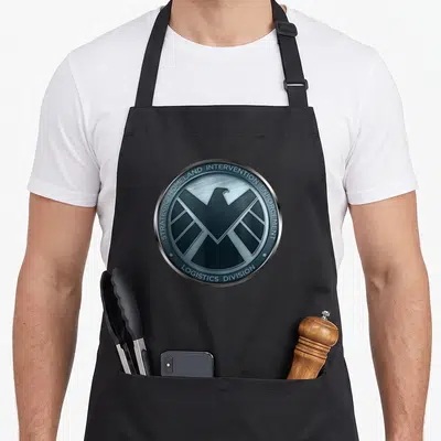 Agent eagles apron - Silver and blue circular badge with eagle and strategic homeland intervention enforcement text — shown on a black cotton canvas apron against a white background