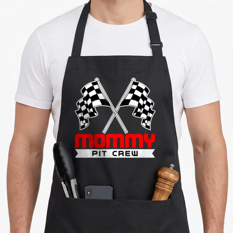 Pit racing crew aprons - Crossed checkered flags above red MOMMY text and white PIT CREW banner — shown on a black cotton canvas apron against a white background