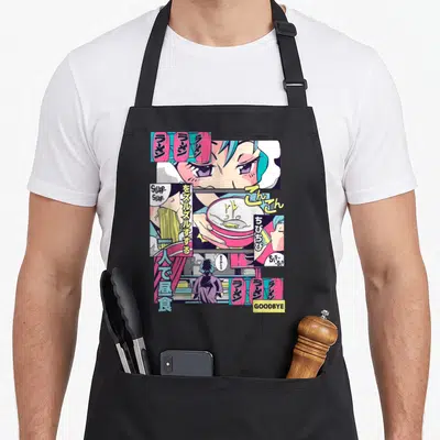 90s kawaii cooking apron - Manga anime girl eating ramen with Japanese text, pink lanterns, and sound effects Slurp Sip — shown on a black cotton canvas apron against a white background