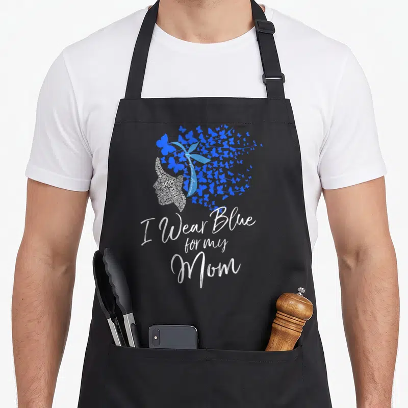 Colon blue mom apron - I Wear Blue for my Mom text with blue butterflies and ribbon silhouette — shown on a black cotton canvas apron against a white background
