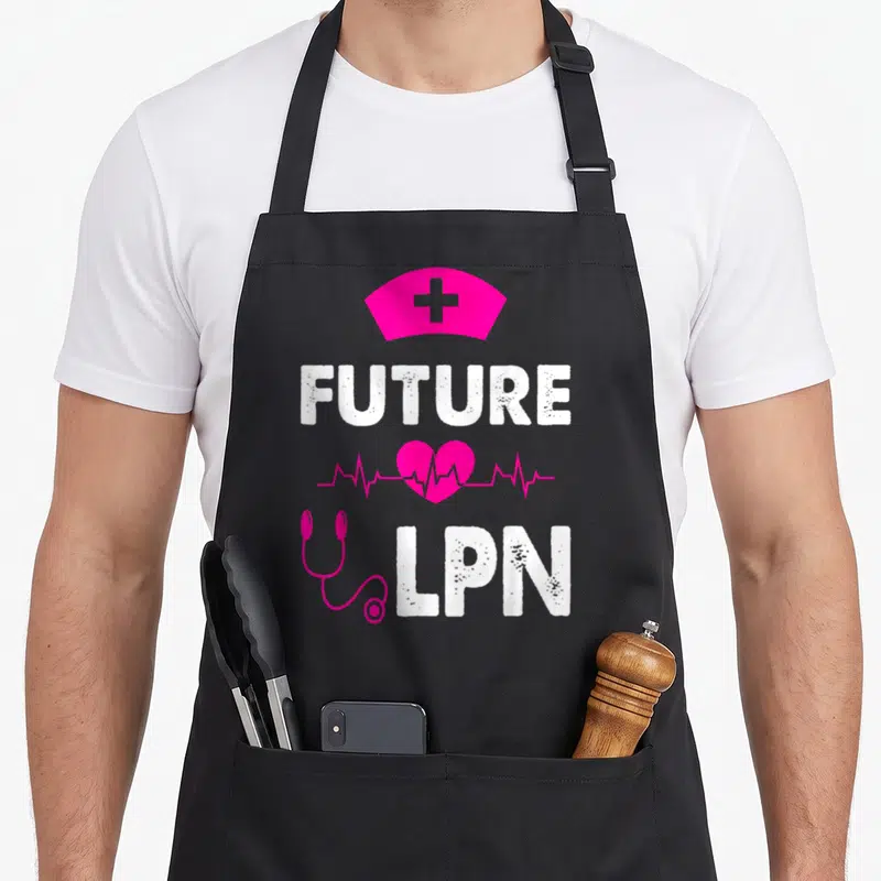 Appreciate nurse apron - Pink nurse cap FUTURE LPN heart stethoscope text on black — shown on a black cotton canvas apron against a white background