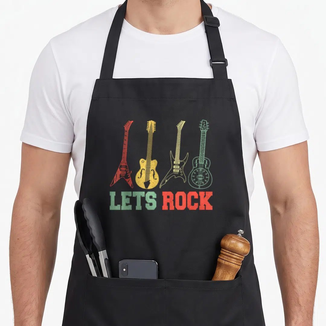 Rock world music apron - Four distressed guitars in red, yellow, and green above LETS ROCK text — shown on a black cotton canvas apron against a white background
