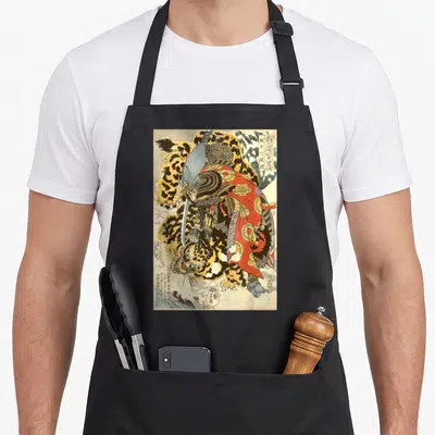 Samurai artwork apron - Retro Japanese woodblock print of samurai in armor fighting a leopard-spotted tiger — shown on a black cotton canvas apron against a white background