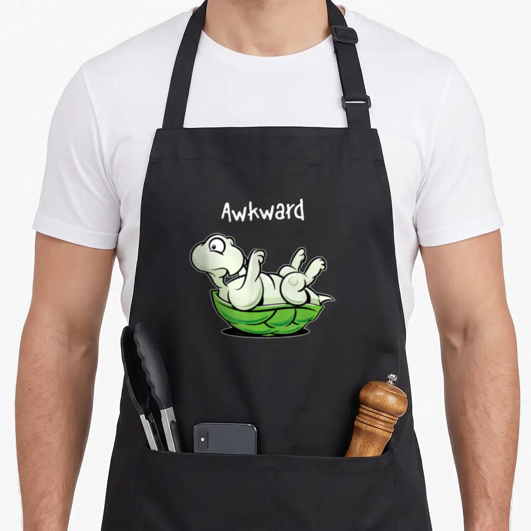 Inverted funny awkward apron - Cartoon turtle lying on back with Awkward text in green and white — shown on a black cotton canvas apron against a white background