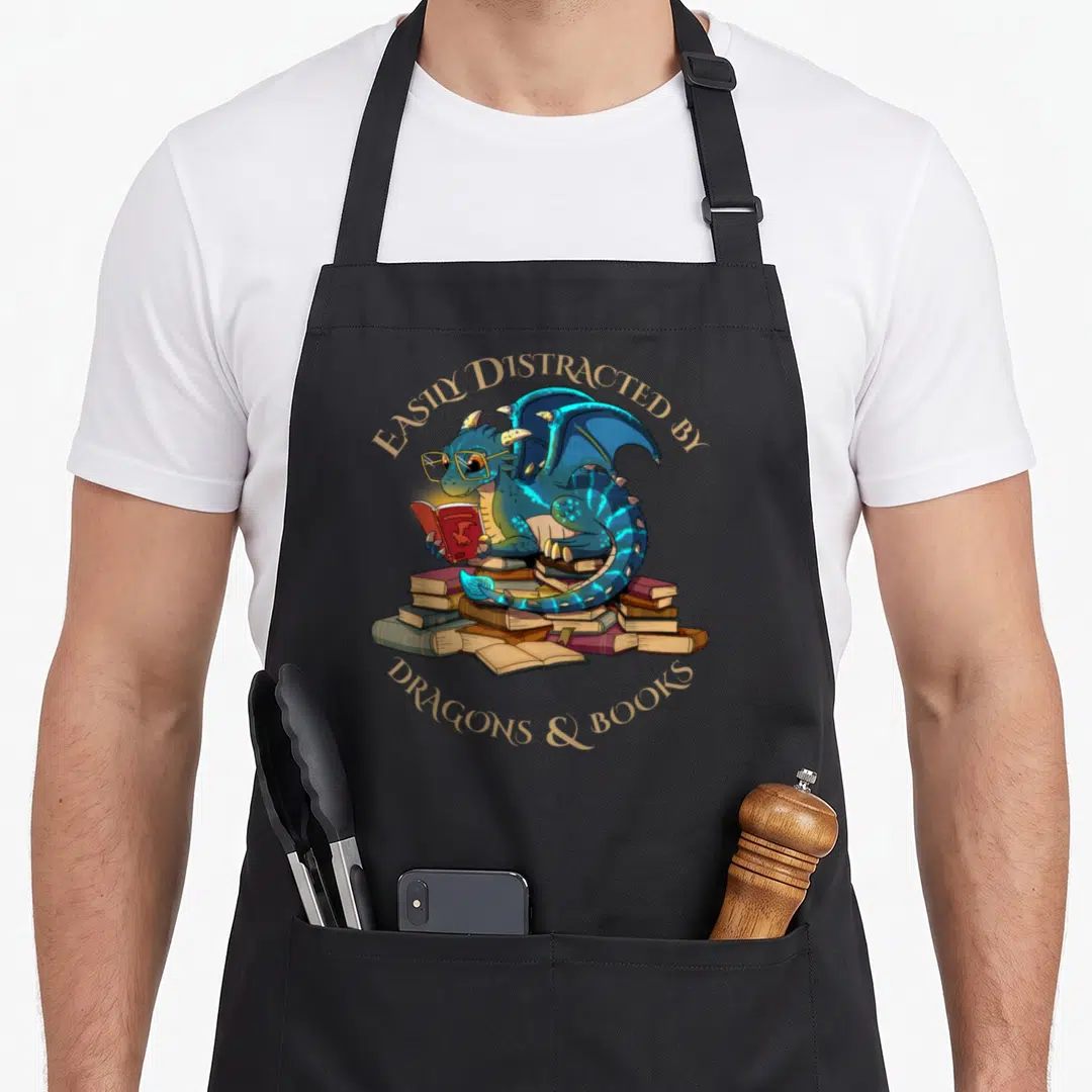 Easily nerd apron - Blue dragon with glasses reading red book on pile of books with gold text — shown on a black cotton canvas apron against a white background