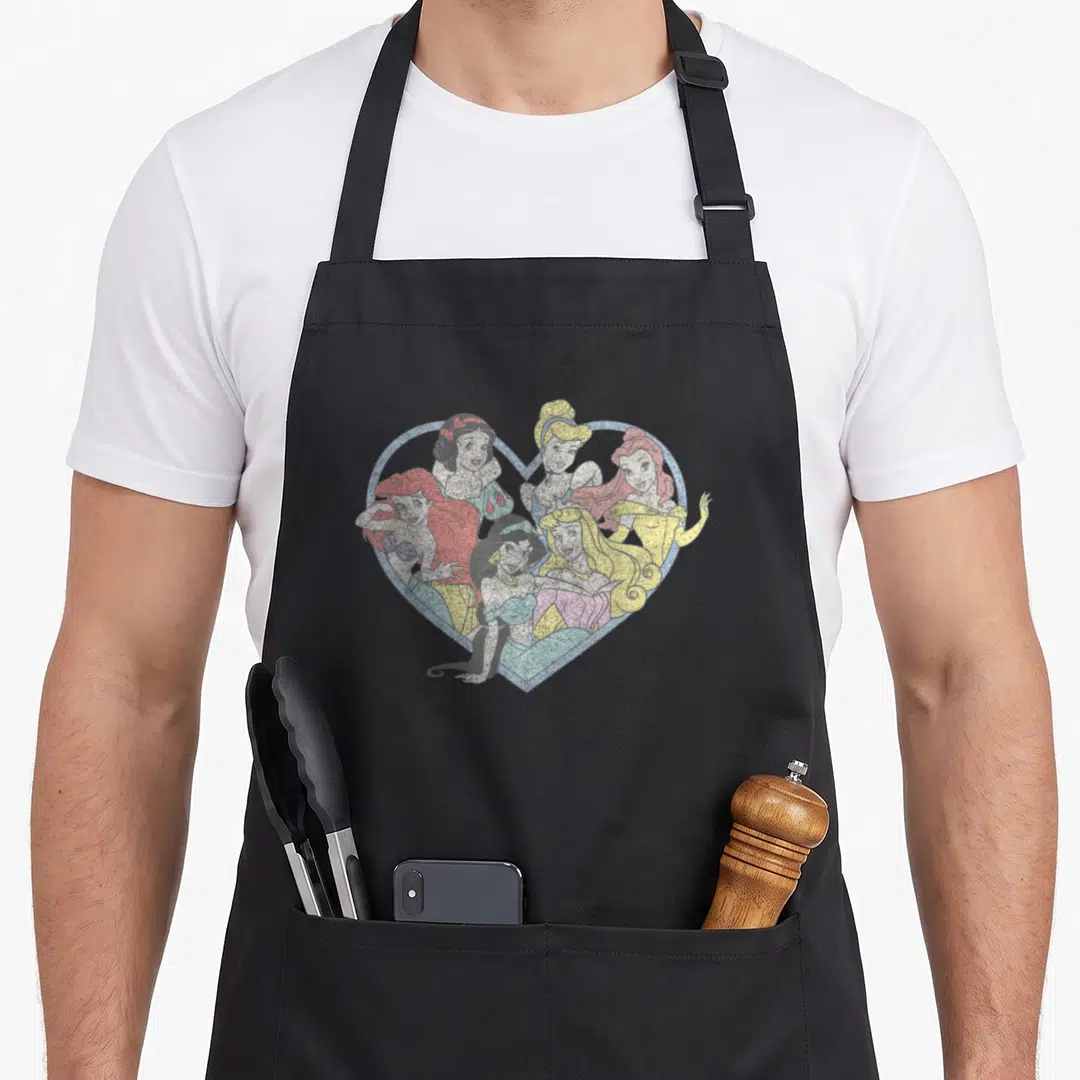 Princess valentine's day apron - Six princesses inside a distressed blue heart outline with red yellow pink and blue — shown on a black cotton canvas apron against a white background