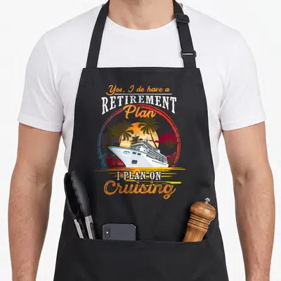 Cruising retirement apron - Retro cruise ship sunset graphic with Yes I do have a retirement plan text — shown on a black cotton canvas apron against a white background