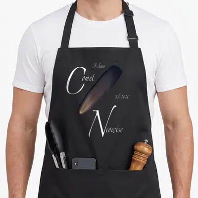 Saw comet apron - I Saw Comet Neowise July 2020 text surrounding a yellow and grey comet illustration — shown on a black cotton canvas apron against a white background