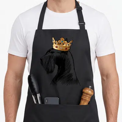 Crown schnauzer apron - Black line art Giant Schnauzer profile wearing an ornate gold crown — shown on a black cotton canvas apron against a white background