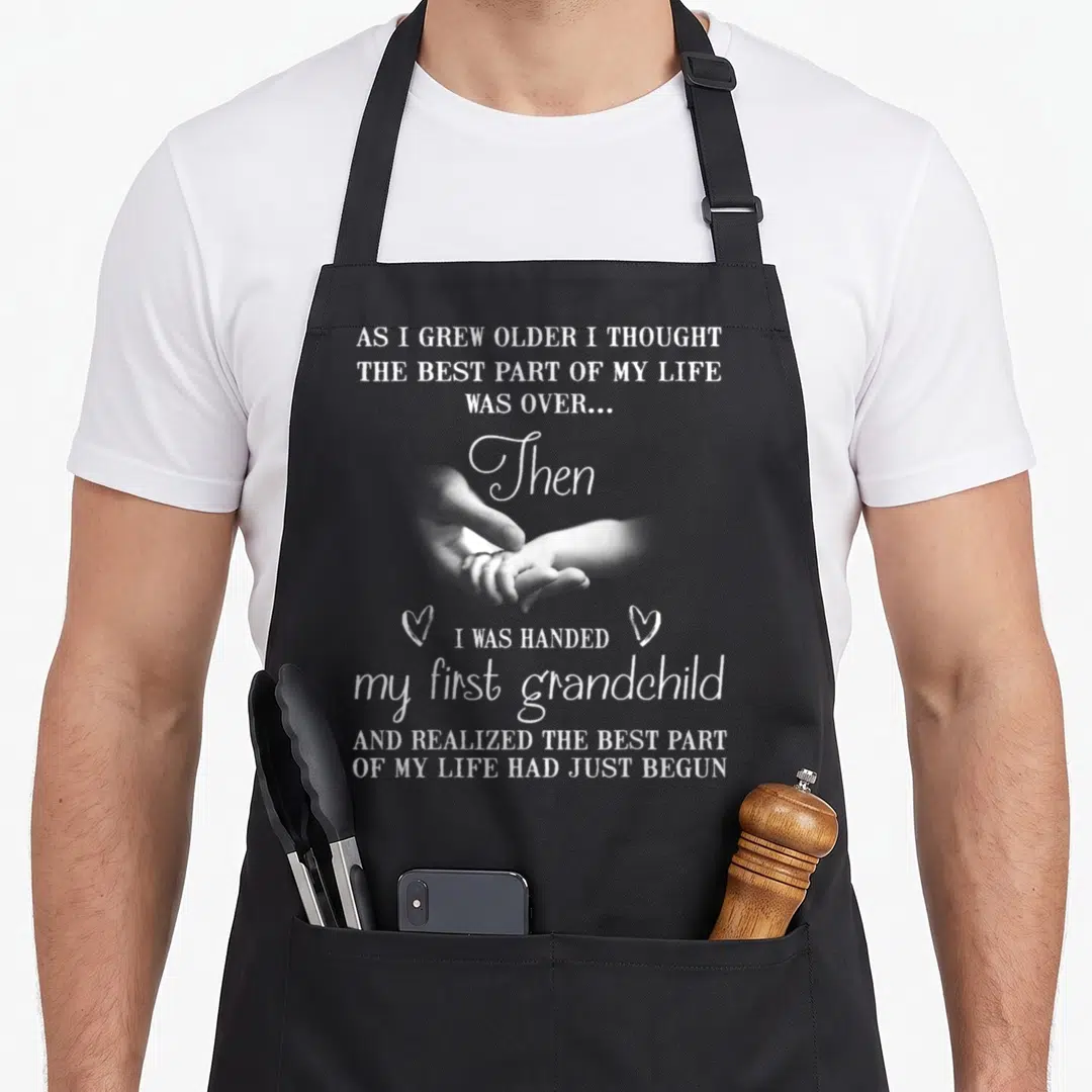 Handed grandma apron - White text and photo of hands holding on grey background with two hearts — shown on a black cotton canvas apron against a white background