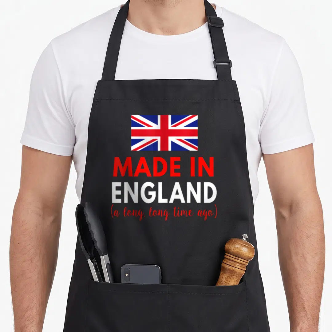 Funny ago birthday apron - Union Jack flag above red and white text reading Made in England a long long time ago — shown on a black cotton canvas apron against a white background