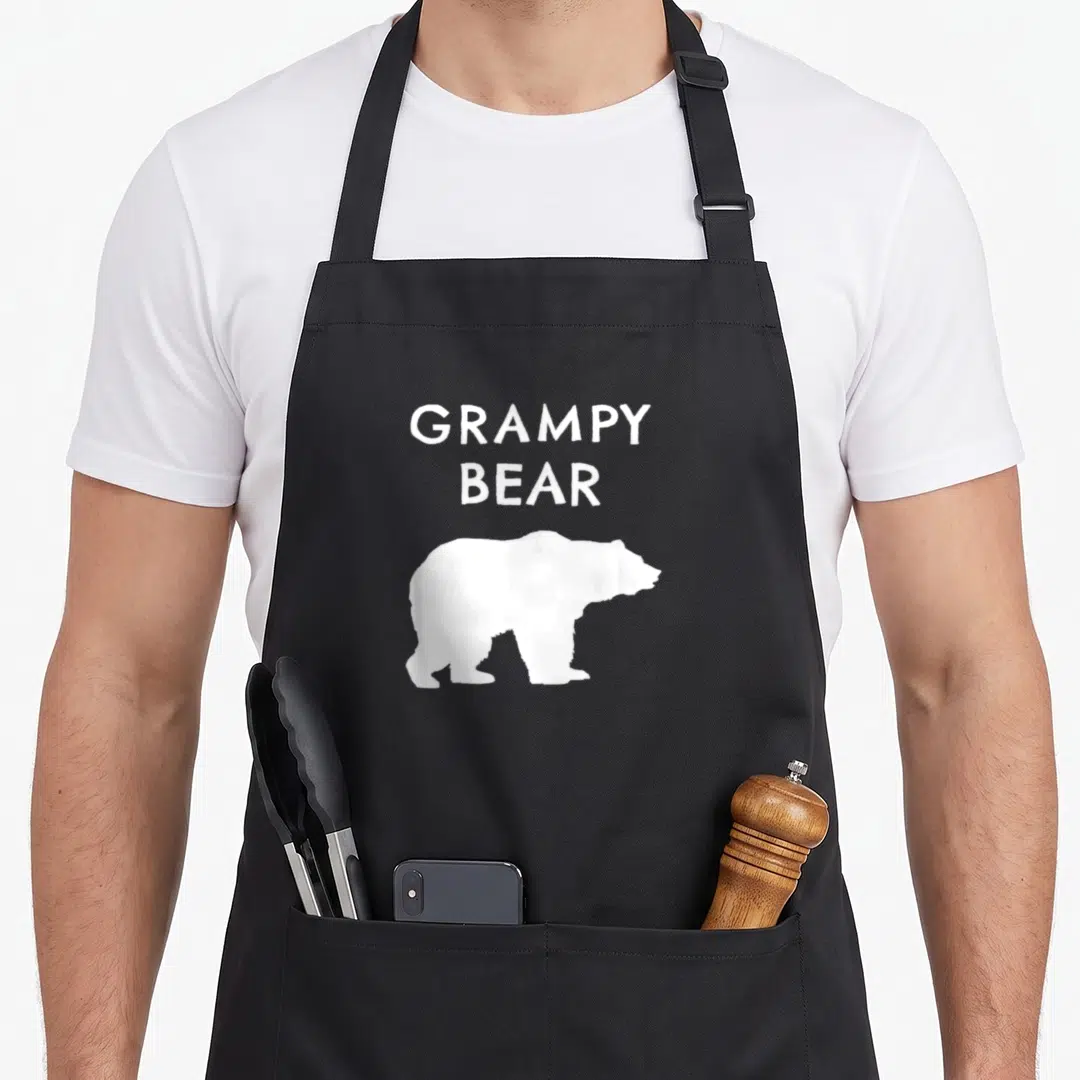 Grampy bear apron - Stacked white GRAMPY BEAR text above a white bear silhouette on dark background — shown on a black cotton canvas apron against a white background