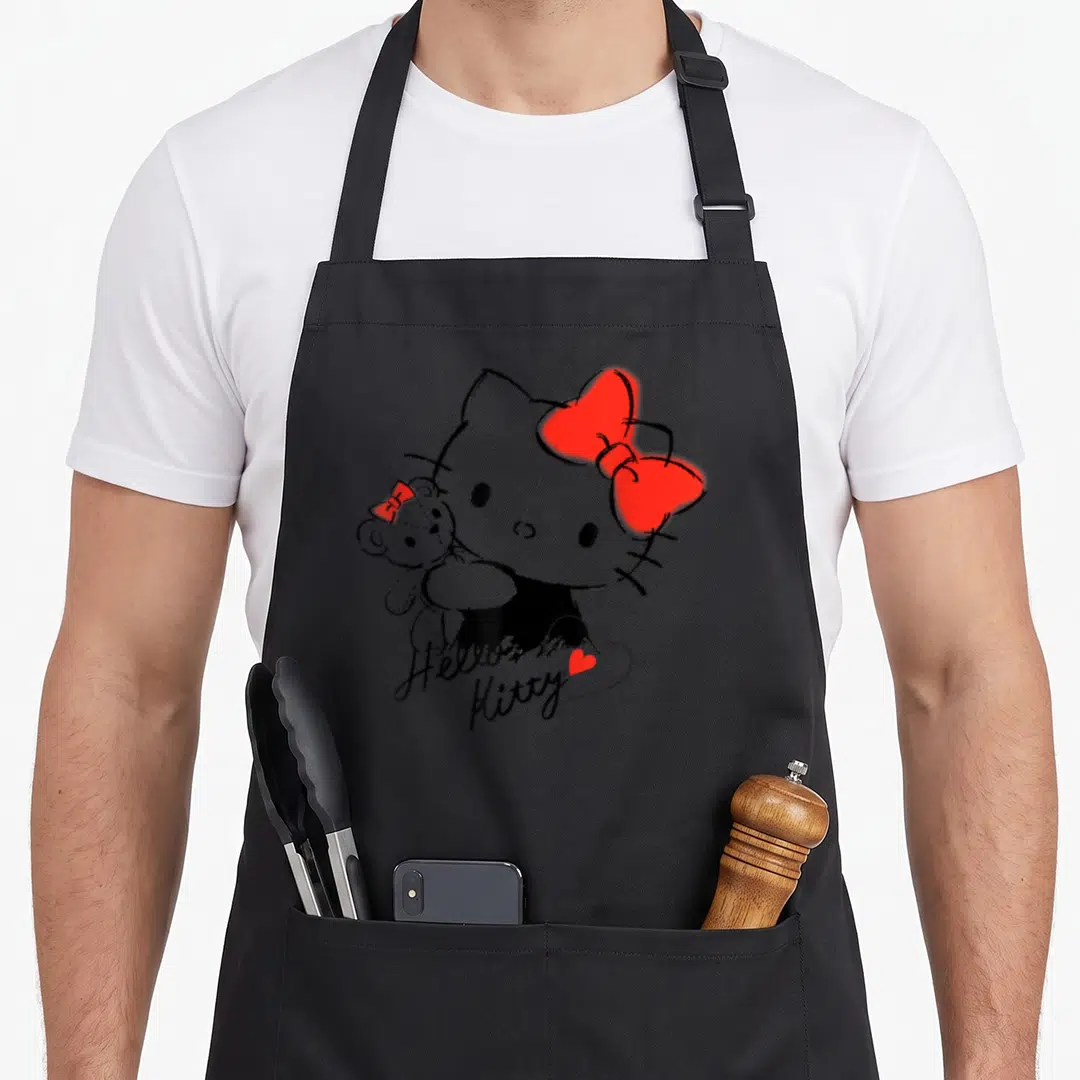 Chum tiny chef apron - Sketchy Hello Kitty holding teddy bear with red bows and cursive text below — shown on a black cotton canvas apron against a white background