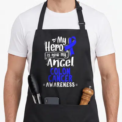 Colorectal patient apron - Blue ribbon and stacked text My Hero is now my Angel Colon Cancer Awareness — shown on a black cotton canvas apron against a white background