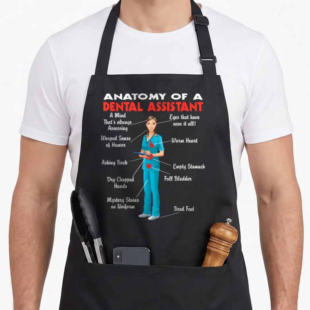 Dental anatomy apron - Cartoon dental assistant with labels for mystery stains, tired feet, and warm heart in blue red — shown on a black cotton canvas apron against a white background
