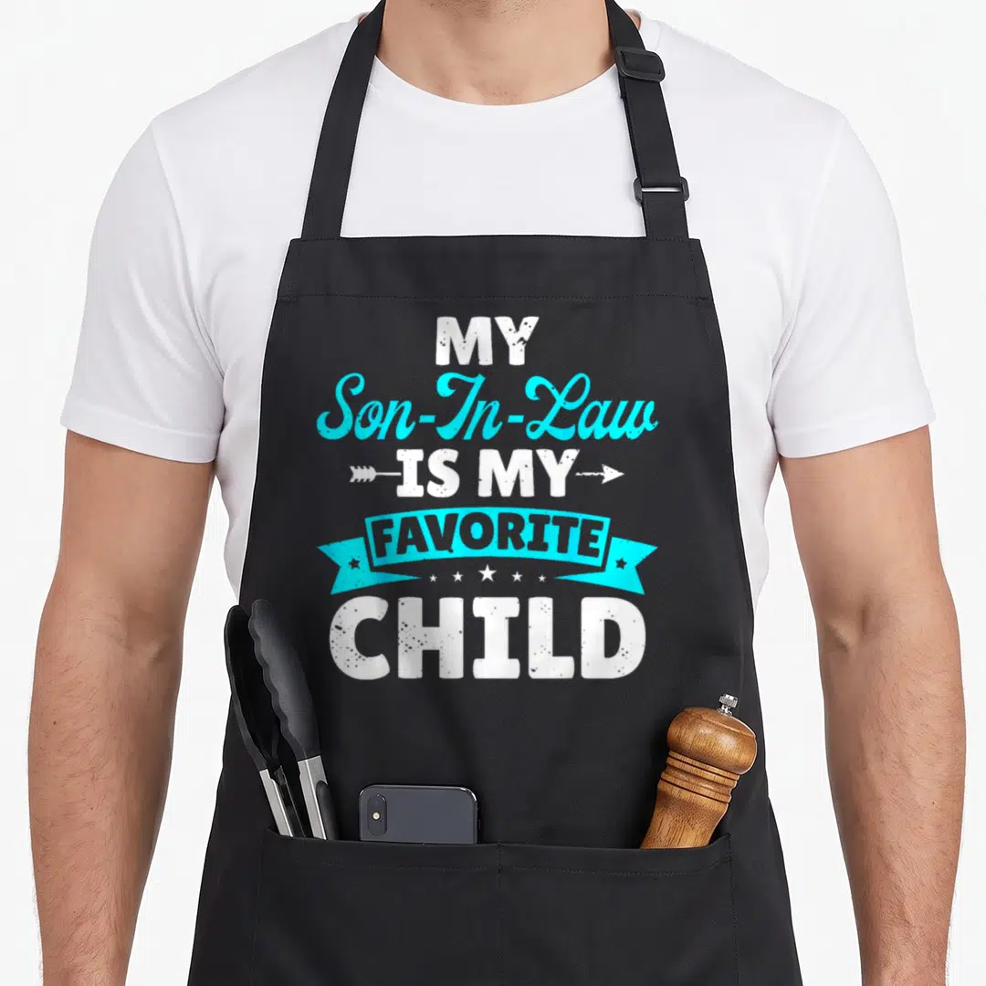 Law family aprons - White and cyan stacked text reading My Son In Law Is My Favorite Child with an arrow and ribbon — shown on a black cotton canvas apron against a white background