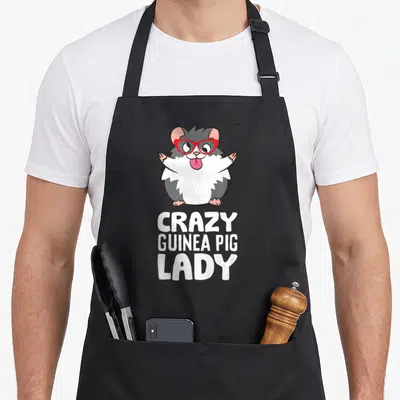 Animal crazy guinea woman apron - Cartoon guinea pig with red glasses above white text CRAZY GUINEA PIG LADY — shown on a black cotton canvas apron against a white background
