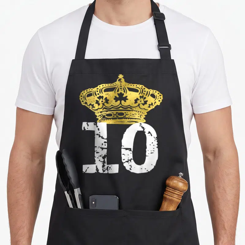 Birthday prince king apron - Gold crown above distressed white number 10 on black fabric — shown on a black cotton canvas apron against a white background