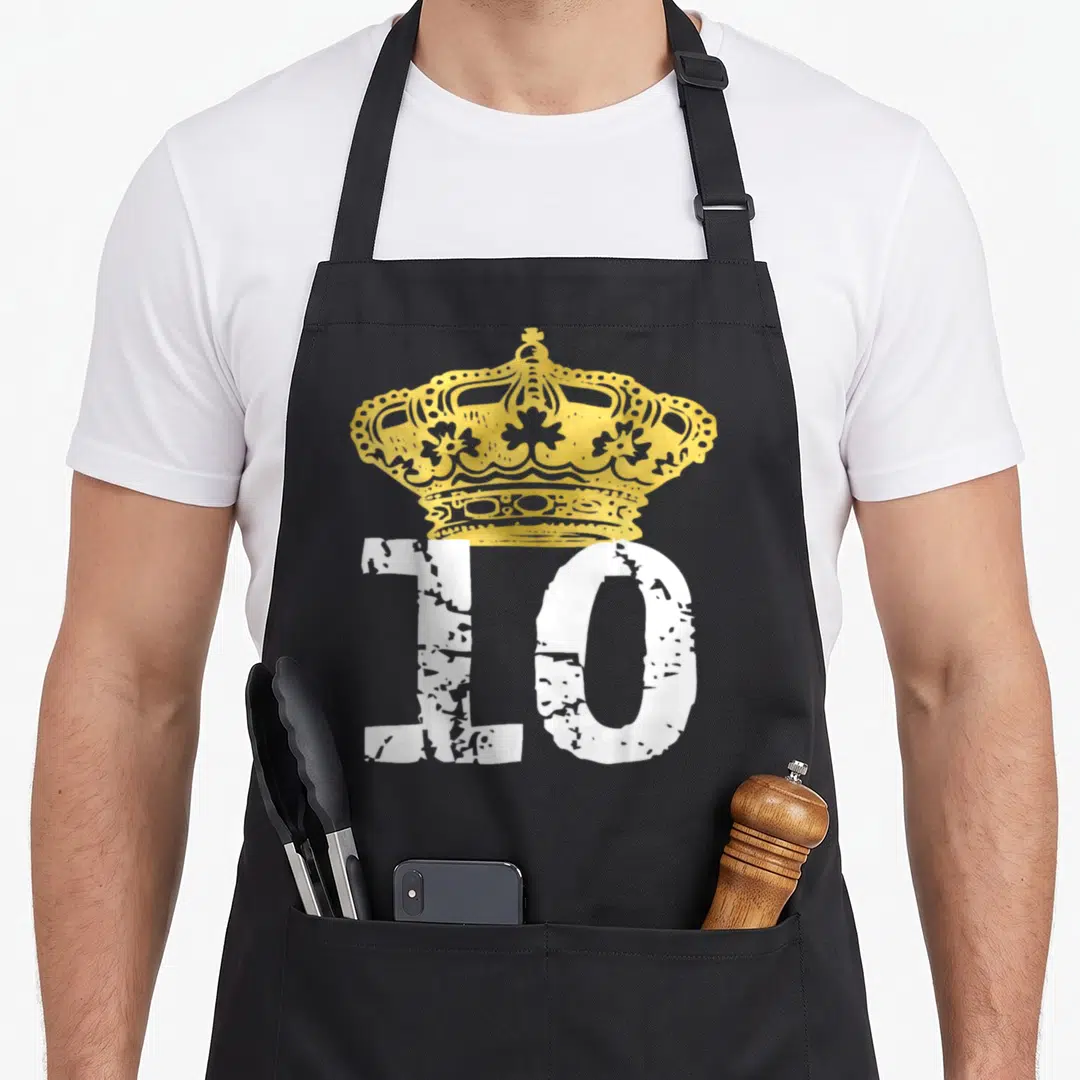 Birthday prince king apron - Gold crown above distressed white number 10 on black fabric — shown on a black cotton canvas apron against a white background