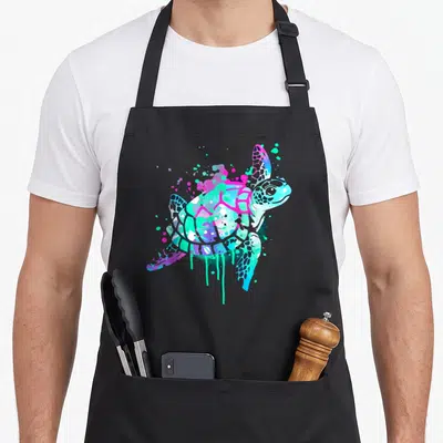 Watercolor animal apron - Stylized sea turtle in cyan magenta blue purple with dripping paint splatters — shown on a black cotton canvas apron against a white background