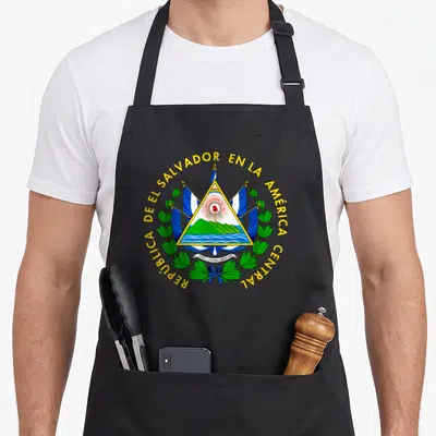Salvador salvadoran apron - Coat of arms with volcano rainbow flags and yellow text arching over green laurel branches — shown on a black cotton canvas apron against a white background