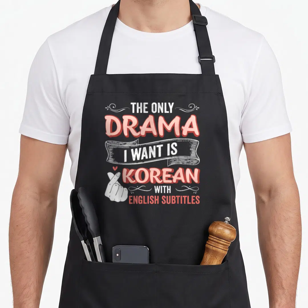 Drama english apron - Pink and white stacked text reading Korean with English subtitles next to a finger heart hand sign — shown on a black cotton canvas apron against a white background