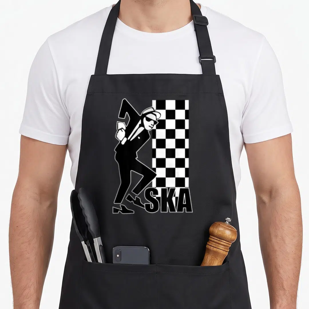 Music ska apron - Dancing man silhouette next to black and white checkered rectangle with SKA text — shown on a black cotton canvas apron against a white background