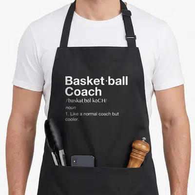 Definition basketball coach apron - White dictionary definition text reading Basketball Coach Like a normal coach — shown on a black cotton canvas apron against a white background