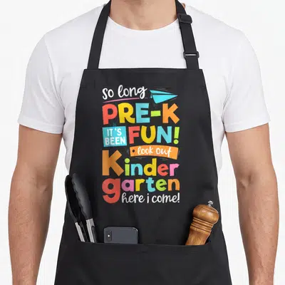 Nursery come and get it apron - Colorful stacked text saying so long pre-k here i come with paper airplane — shown on a black cotton canvas apron against a white background