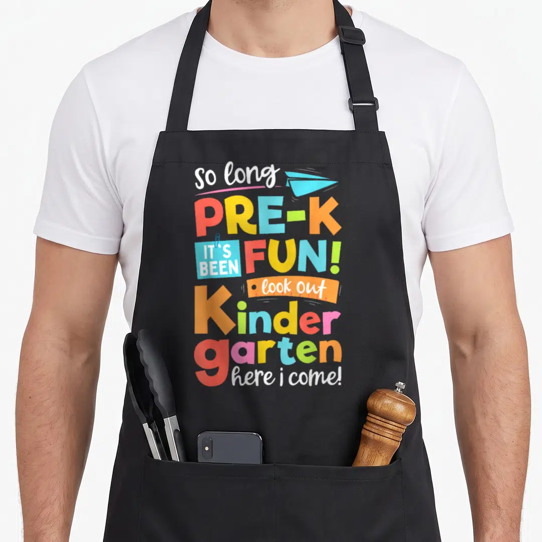 Nursery come and get it apron - Colorful stacked text saying so long pre-k here i come with paper airplane — shown on a black cotton canvas apron against a white background