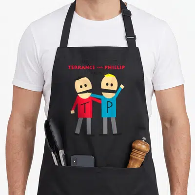 Terrance park apron - Two cartoon figures in red and blue shirts with T and P initials under stacked show title text — shown on a black cotton canvas apron against a white background