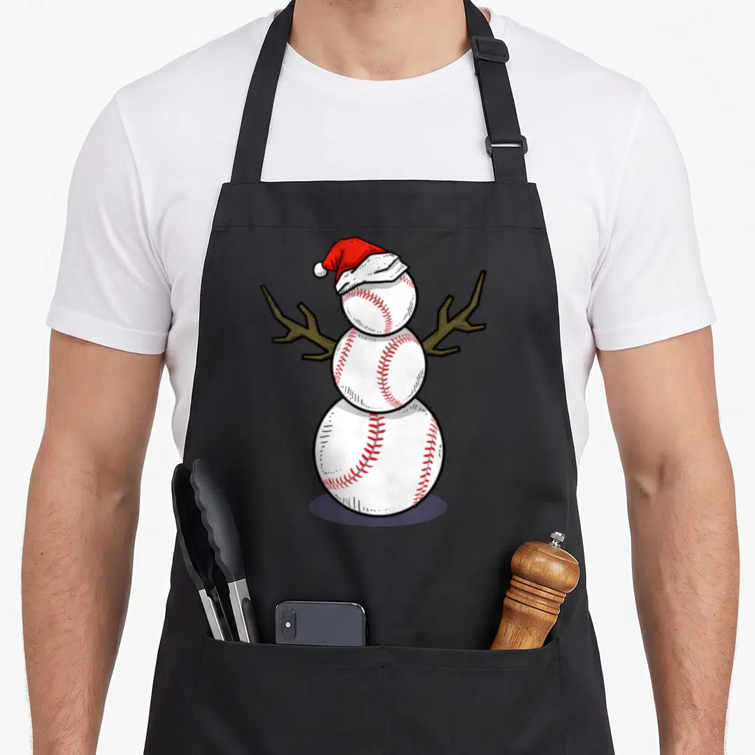 July snowman apron - Cartoon snowman made of three white baseballs with red stitching and a red Santa hat — shown on a black cotton canvas apron against a white background