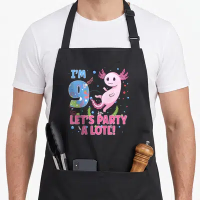 Axolotl motif birthday apron - Pink axolotl next to blue number 9 with text I'M 9 LET'S PARTY A LOTL and bubbles — shown on a black cotton canvas apron against a white background