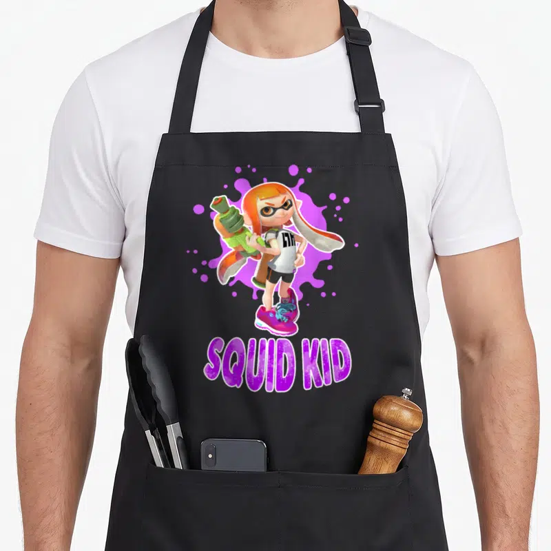 Splat squid lady apron - Inkling girl holding green weapon over purple splatter with SQUID KID text below — shown on a black cotton canvas apron against a white background