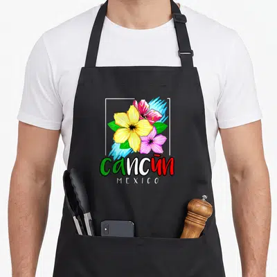 Souvenir spring aprons - Yellow pink and red flowers with Cancun MEXICO text and white frame — shown on a black cotton canvas apron against a white background