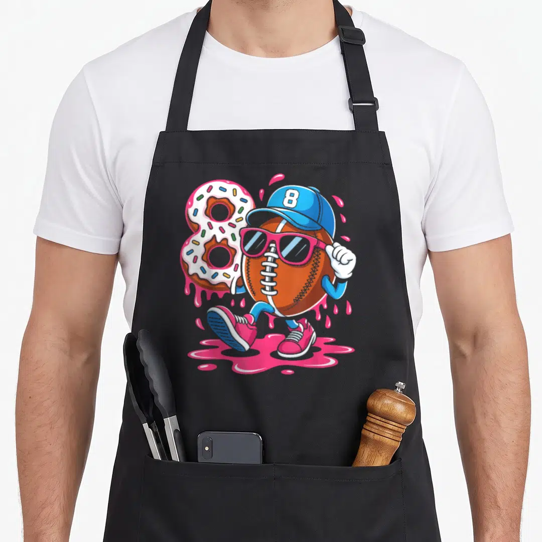 Football ice cream apron - Walking football character with sunglasses next to number 8 donut and pink splashes — shown on a black cotton canvas apron against a white background