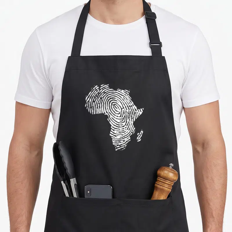 Fingerprint pride apron - White fingerprint pattern forming the silhouette of the African continent on a dark background — shown on a black cotton canvas apron against a white background