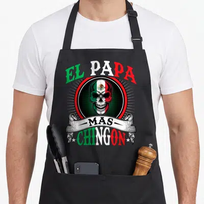 Husband mexican apron - Skull with Mexican flag pattern under EL PAPA MAS CHINGON text in green red and white — shown on a black cotton canvas apron against a white background