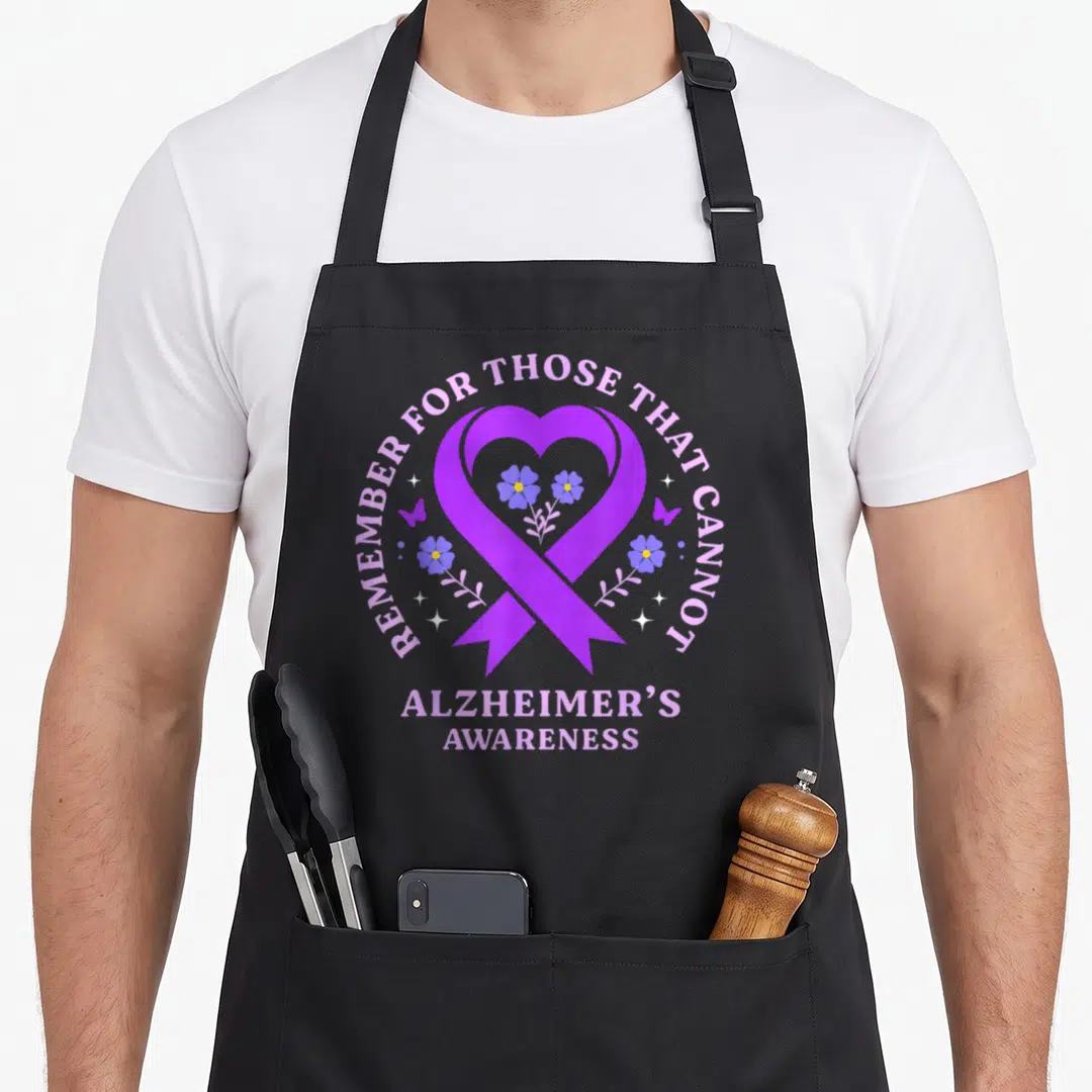 Remember alzheimer's aprons - Purple heart ribbon with blue flowers and stars, text: Remember For Those That Cannot — shown on a black cotton canvas apron against a white background