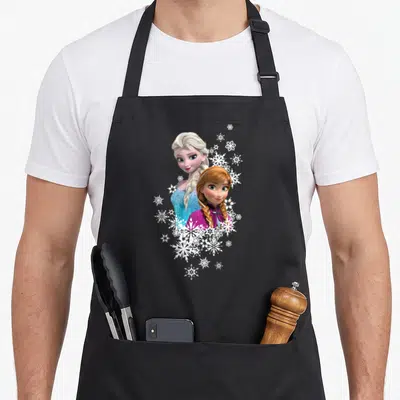 Anna frozen apron - Elsa and Anna portrait with white snowflake cluster in blue and magenta photo art — shown on a black cotton canvas apron against a white background