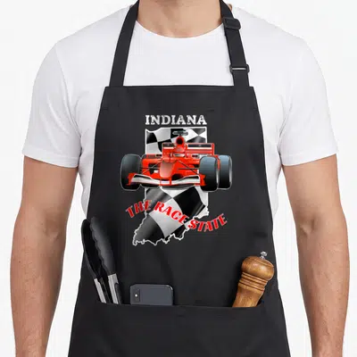 Indianapolis checkered apron - Red race car over checkered Indiana state shape with INDIANA and THE RACE STATE text — shown on a black cotton canvas apron against a white background