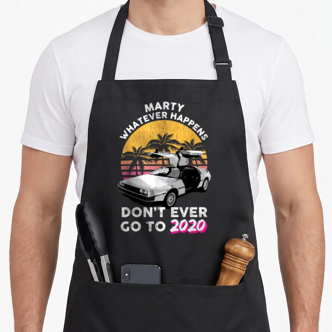 Marty car apron - Retro car with open gullwing doors under yellow sun and palm trees with sarcastic 2020 text — shown on a black cotton canvas apron against a white background