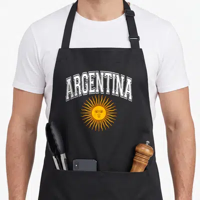 Argentina argentine girl apron - Arched white ARGENTINA text above a yellow Sun of May with a face and radiating rays — shown on a black cotton canvas apron against a white background